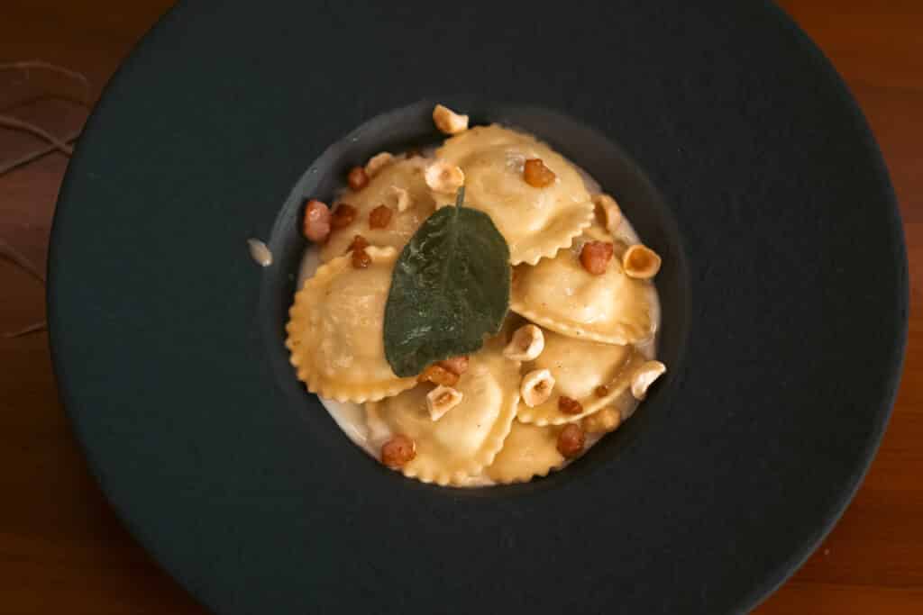 Ravioli ripieni di mele IGP di Cuneo e verza conditi con crema di toma piemontese, nocciole e guanciale croccanteRavioli ripieni di mele IGP di Cuneo e verza conditi con crema di toma piemontese, nocciole e guanciale croccante